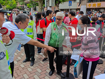 Volunteers are maintaining order as students are entering a test room to take part in the National college entrance examination in Shanghai,...