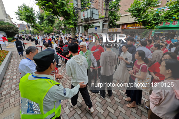 Volunteers are maintaining order as students are entering a test room to take part in the National college entrance examination in Shanghai,...