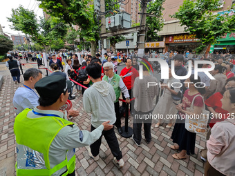 Volunteers are maintaining order as students are entering a test room to take part in the National college entrance examination in Shanghai,...