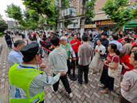 Volunteers are maintaining order as students are entering a test room to take part in the National college entrance examination in Shanghai,...