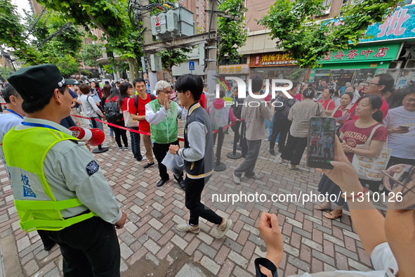 Volunteers are maintaining order as students are entering a test room to take part in the National college entrance examination in Shanghai,...