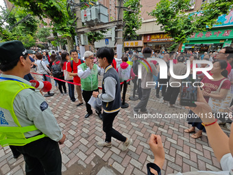 Volunteers are maintaining order as students are entering a test room to take part in the National college entrance examination in Shanghai,...