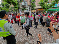 Volunteers are maintaining order as students are entering a test room to take part in the National college entrance examination in Shanghai,...