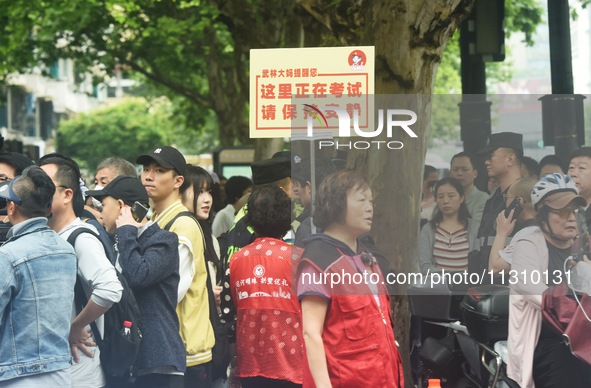 Volunteers are reminding passers-by to keep quiet outside a college entrance exam in Hangzhou, China, on June 7, 2024. 