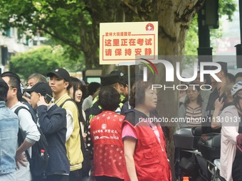 Volunteers are reminding passers-by to keep quiet outside a college entrance exam in Hangzhou, China, on June 7, 2024. (