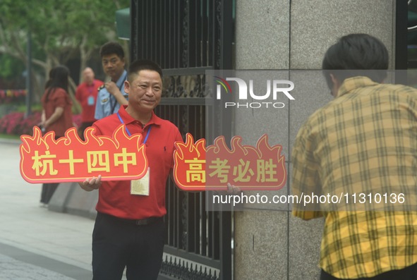 A teacher is delivering exams and wishing students well outside a national college entrance examination (GAOKAO) point in Hangzhou, China, o...