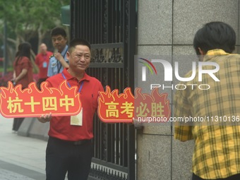 A teacher is delivering exams and wishing students well outside a national college entrance examination (GAOKAO) point in Hangzhou, China, o...