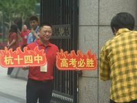 A teacher is delivering exams and wishing students well outside a national college entrance examination (GAOKAO) point in Hangzhou, China, o...