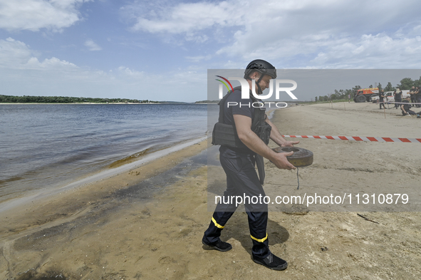 An EOD expert is carrying an old anti-tank mine left from past wars found in the Dnipro River bed during the training of State Emergency Ser...