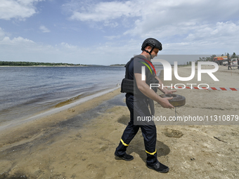 An EOD expert is carrying an old anti-tank mine left from past wars found in the Dnipro River bed during the training of State Emergency Ser...