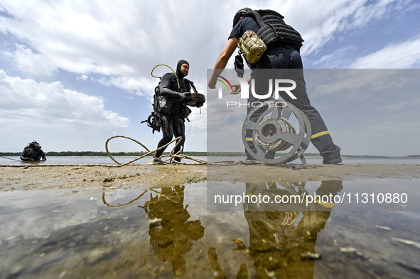 A diver is handing over an anti-tank mine from past wars found on the Dnipro River bottom to an EOD expert during the training of State Emer...