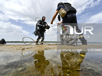 A diver is handing over an anti-tank mine from past wars found on the Dnipro River bottom to an EOD expert during the training of State Emer...