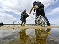 A diver is handing over an anti-tank mine from past wars found on the Dnipro River bottom to an EOD expert during the training of State Emer...