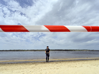 An EOD expert is holding a bomb on the Dnipro River bank behind red and white caution tape during the training of State Emergency Service pe...