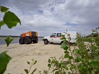 A Bohun-2 snowmobile is towing an SES vehicle, which is unable to reach the site of an explosive device due to sandy soil and a flooded floo...