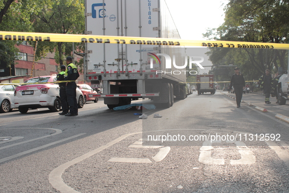 Traffic police are cordoning off the area where a cargo truck is running over a man of approximately 35 years old while he is driving his tr...