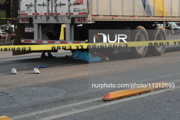 A man of approximately 35 years old is under a cargo truck after losing his life being run over while he is driving his tricycle, on Eje 2 N...