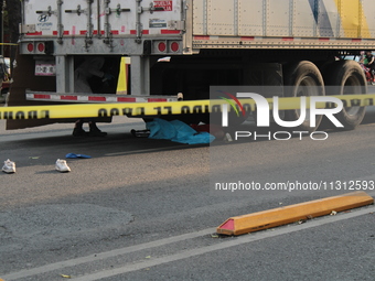 A man of approximately 35 years old is under a cargo truck after losing his life being run over while he is driving his tricycle, on Eje 2 N...