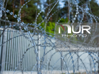 A general view of the area with barbed wire at a sign by the border wall in a forest in Podlasie, Poland, on June 6, 2024. (