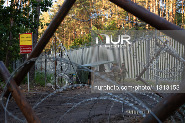 Soldiers are speaking as they are keeping watch and observing at a post in the area by the border wall in a forest in Podlasie, Poland, on J...