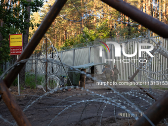 Soldiers are speaking as they are keeping watch and observing at a post in the area by the border wall in a forest in Podlasie, Poland, on J...