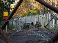 Soldiers are speaking as they are keeping watch and observing at a post in the area by the border wall in a forest in Podlasie, Poland, on J...