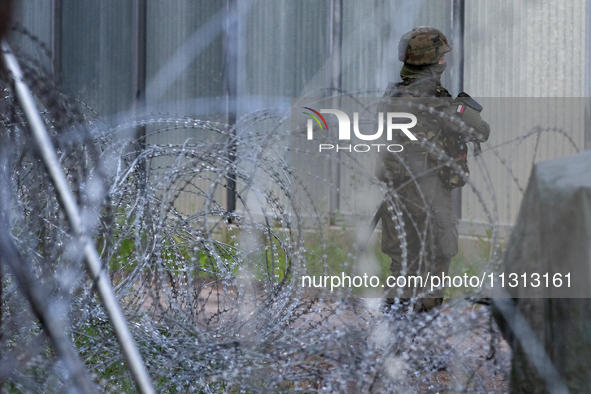 A soldier is keeping watch and observing the area by the border wall in a forest in Podlasie, Poland, on June 6, 2024. 