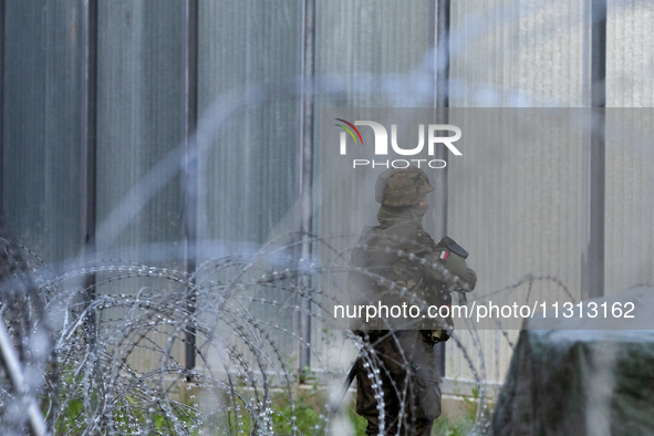 A soldier is keeping watch and observing the area by the border wall in a forest in Podlasie, Poland, on June 6, 2024. 