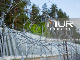 A general view of the area with barbed wire at a sign by the border wall in a forest in Podlasie, Poland, on June 6, 2024. (