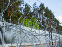 A general view of the area with barbed wire at a sign by the border wall in a forest in Podlasie, Poland, on June 6, 2024. (