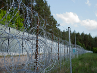 A general view of the area with barbed wire at a sign by the border wall in a forest in Podlasie, Poland, on June 6, 2024. (