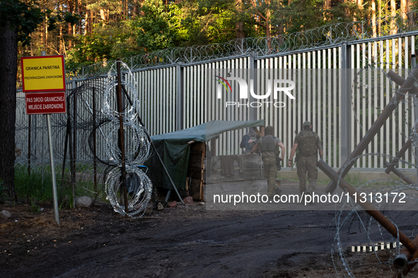 Soldiers are speaking as they are keeping watch and observing at a post in the area by the border wall in a forest in Podlasie, Poland, on J...