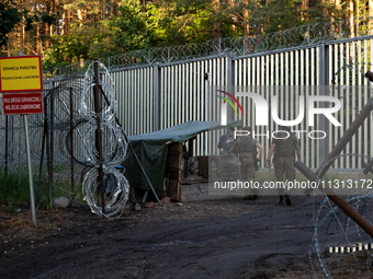 Soldiers are speaking as they are keeping watch and observing at a post in the area by the border wall in a forest in Podlasie, Poland, on J...