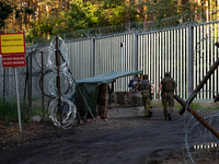 Soldiers are speaking as they are keeping watch and observing at a post in the area by the border wall in a forest in Podlasie, Poland, on J...