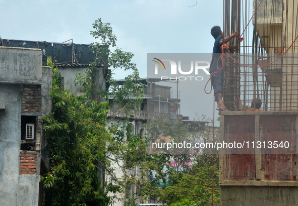 Workers are working using a rope as a safety measure at an under-construction building site in Siliguri, India, on June 8, 2024. 