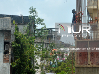 Workers are working using a rope as a safety measure at an under-construction building site in Siliguri, India, on June 8, 2024. (