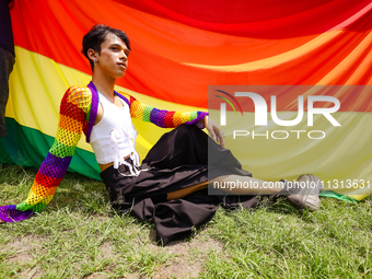 A participant is posing for a photo sitting next to the pride flag while taking part in the annual Nepal Pride Parade in Kathmandu, Nepal, o...