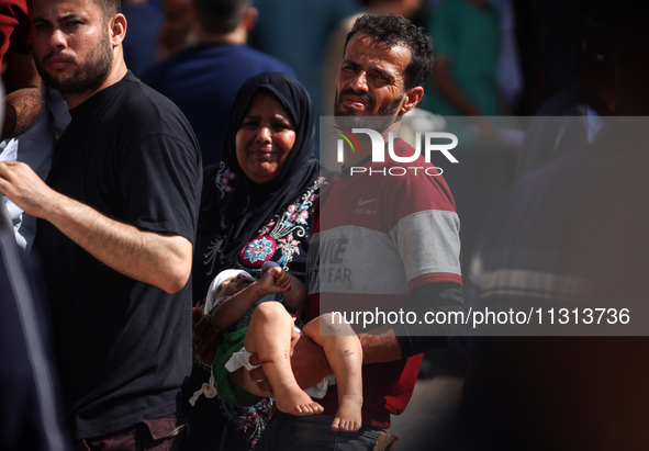 A man is carrying an injured boy at al-Aqsa Martyrs Hospital in Deir al-Balah, in the central Gaza Strip, following the Israeli bombardment...