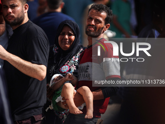 A man is carrying an injured boy at al-Aqsa Martyrs Hospital in Deir al-Balah, in the central Gaza Strip, following the Israeli bombardment...