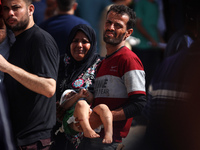 A man is carrying an injured boy at al-Aqsa Martyrs Hospital in Deir al-Balah, in the central Gaza Strip, following the Israeli bombardment...