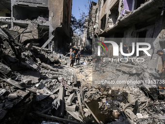 Palestinians are walking on the rubble of destroyed buildings following operations by the Israeli Special Forces in the Nuseirat camp, in th...