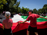 Girls help wave an enormous Palestinian flag during a demonstration encircling the White House, forming a ‘red line’ to call for a end to Is...