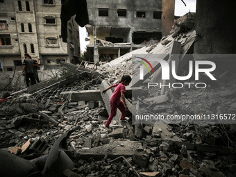 A Palestinian girl is walking over debris to get to a building a day after an operation by the Israeli Special Forces in the Nuseirat camp,...