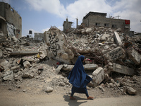 Palestinians are walking past debris a day after an operation by the Israeli Special Forces in the Nuseirat camp, in the central Gaza Strip,...