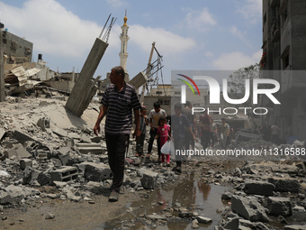 Palestinians are walking past debris a day after an operation by the Israeli Special Forces in the Nuseirat camp, in the central Gaza Strip,...