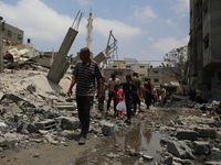 Palestinians are walking past debris a day after an operation by the Israeli Special Forces in the Nuseirat camp, in the central Gaza Strip,...