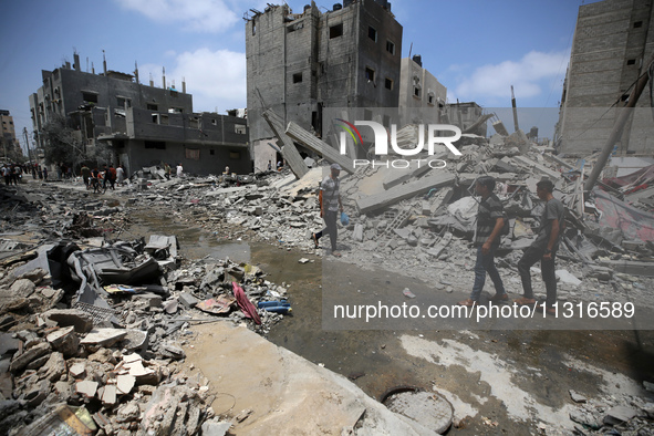 Palestinians are walking past debris a day after an operation by the Israeli Special Forces in the Nuseirat camp, in the central Gaza Strip,...