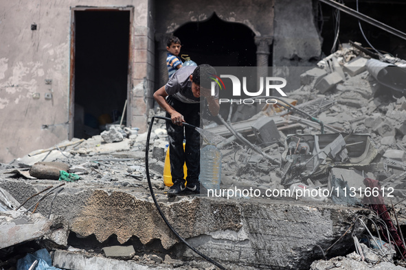 A Palestinian boy is pouring water over himself amidst a heatwave a day after an operation by the Israeli Special Forces in the Nuseirat cam...