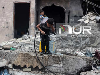 A Palestinian boy is pouring water over himself amidst a heatwave a day after an operation by the Israeli Special Forces in the Nuseirat cam...