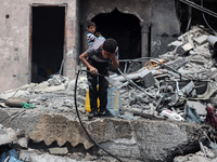 A Palestinian boy is pouring water over himself amidst a heatwave a day after an operation by the Israeli Special Forces in the Nuseirat cam...